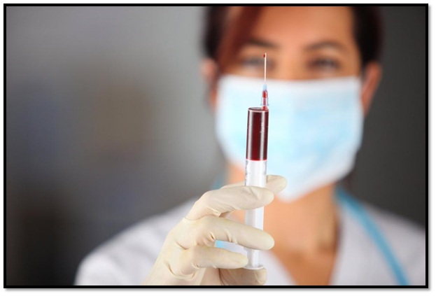 A woman holding up a syringe with blood in it.