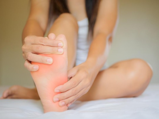A woman is holding her foot in the middle of her leg.