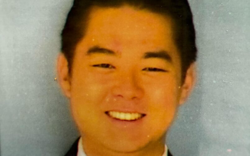 A man in a suit and tie smiling for the camera.
