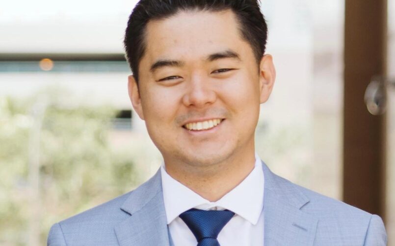 A man in a suit and tie smiling for the camera.