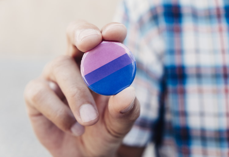 Hand holding bisexual pride button.