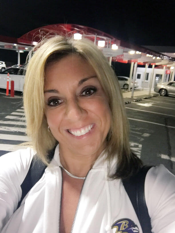 Smiling woman in white zip-up jacket.